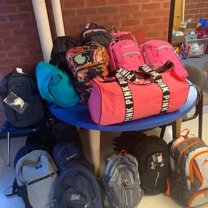 Backpacks and duffels piled on a round table
